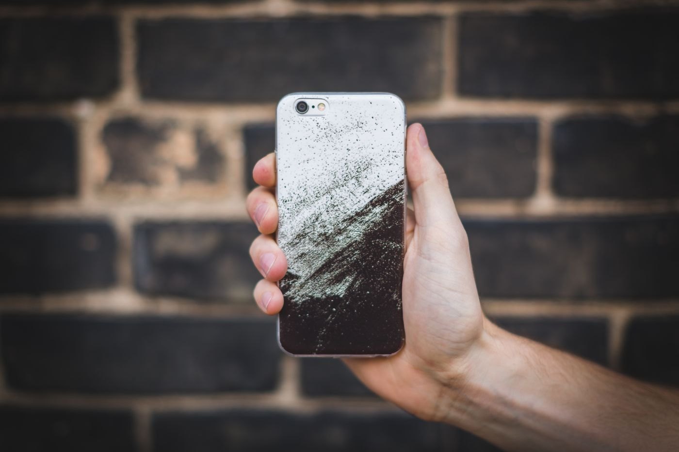 Hand holding a smartphone in front of a wall