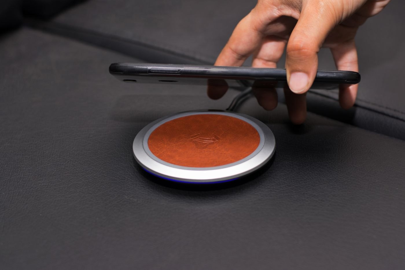 Hand positioning a phone above a charging pad