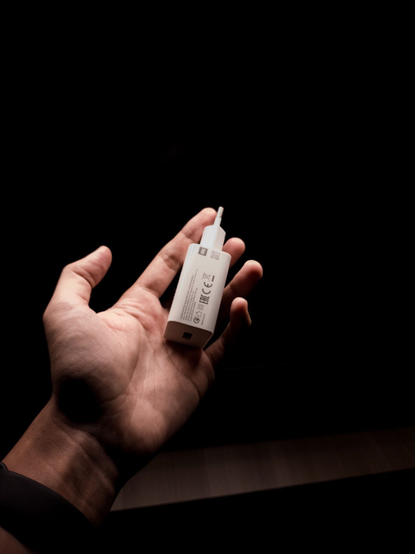 Hand holding a compact replacement power adapter