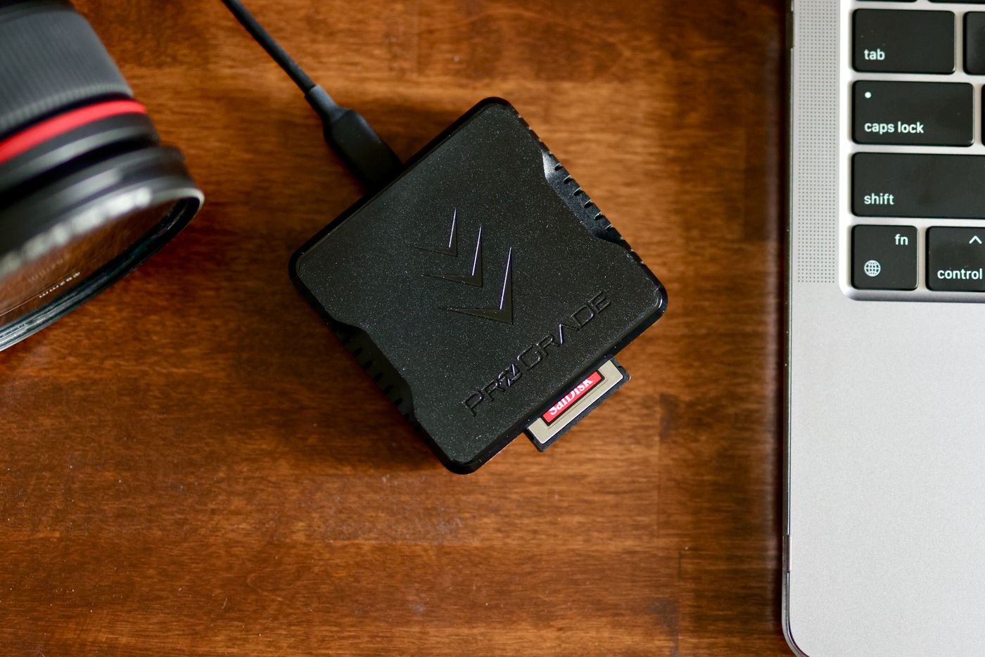 Memory card reader beside a laptop and camera lens