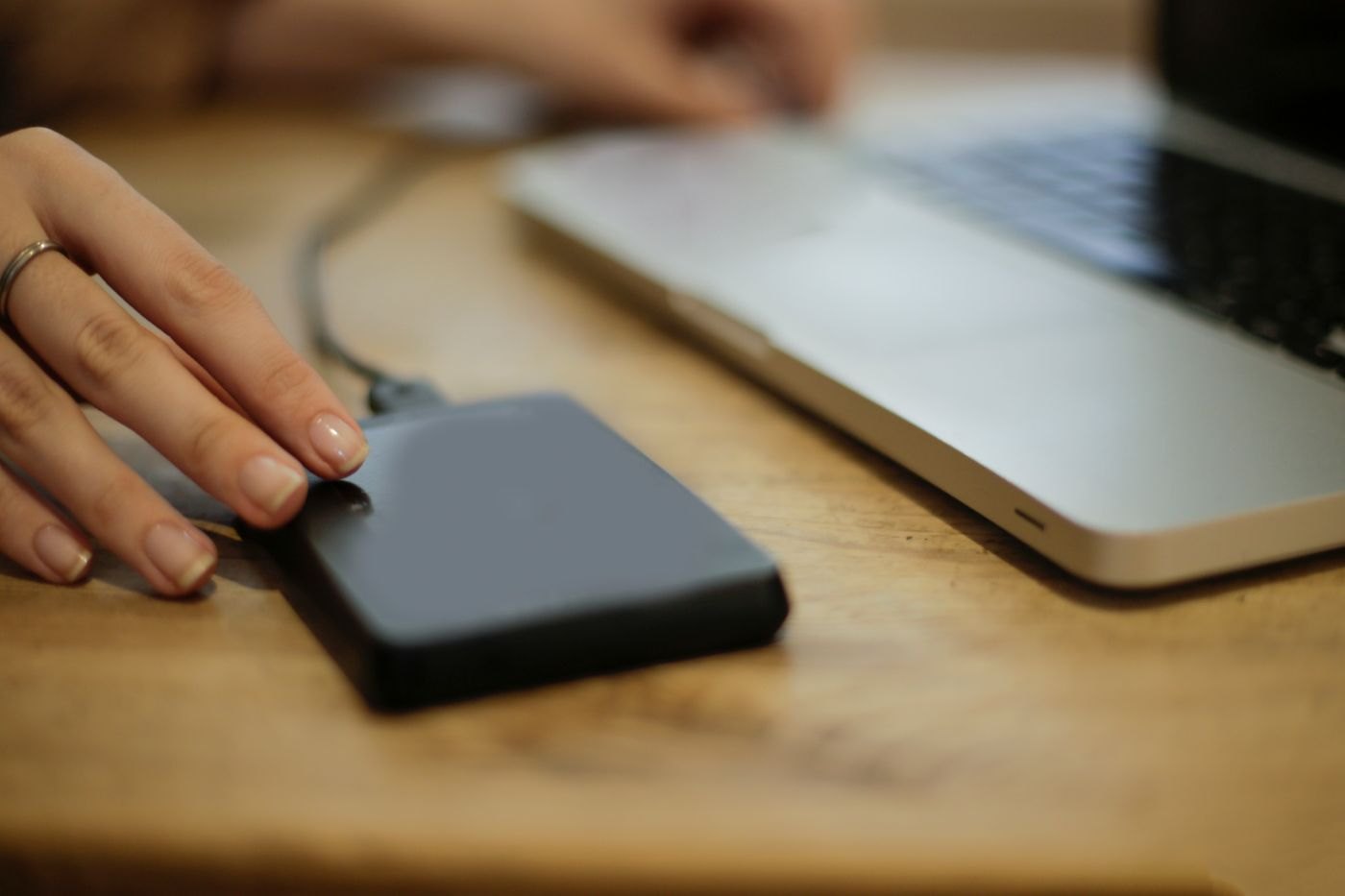 Hand beside an external storage drive on a desk