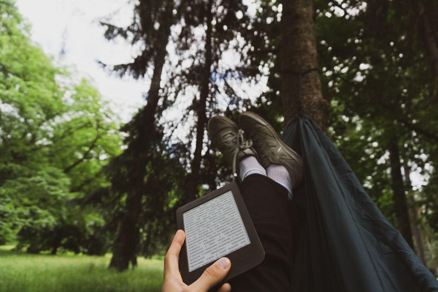 Person reading an e-reader outdoors in a hammock