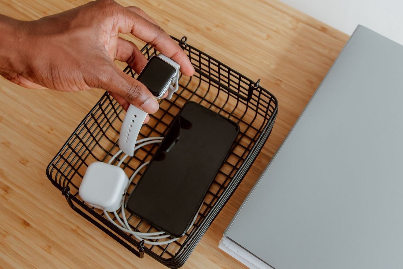 Phone charger and watch arranged in a small wire basket